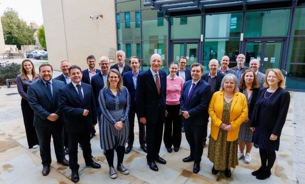 Commissioners including Sir John Armitt shown alongside Mayor Nik Johnson standing outside Cambridge and Peterborough Combined Authority offices, Huntingdon