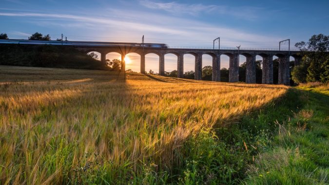 A train running across a viaduct at sunset