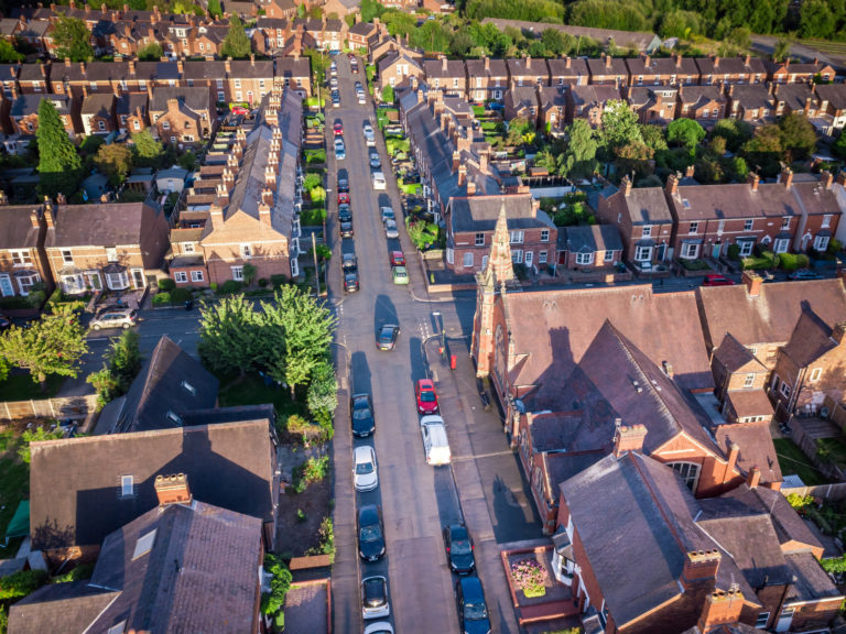 Sun setting with atmospheric effect over traditional British houses and tree lined streets.