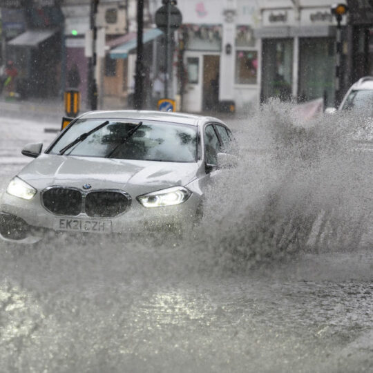 Car driving through a large puddle, splashing rainwater