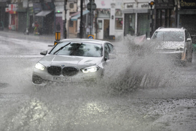 Car driving through a large puddle, splashing rainwater