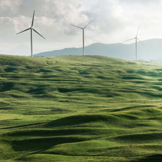 Three Windmills on green hills in front of a stormy sky