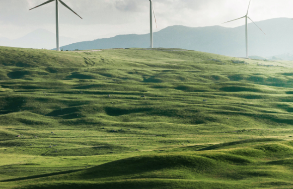 Three Windmills on green hills in front of a stormy sky