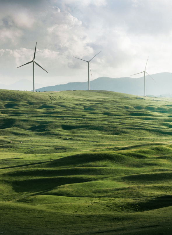 Three Windmills on green hills in front of a stormy sky