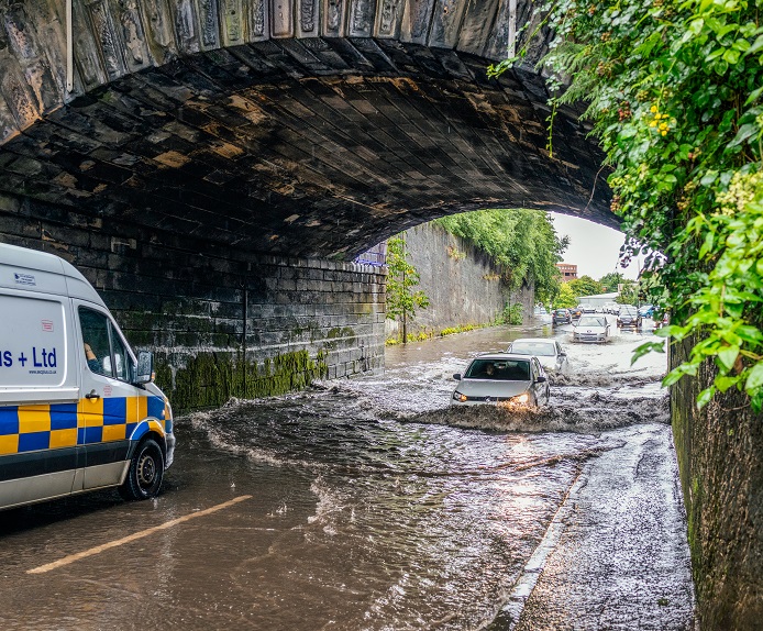 Picture showing a car stuck in floodwater under a bridge