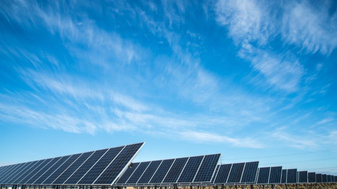 Field of solar panels against a blue sky