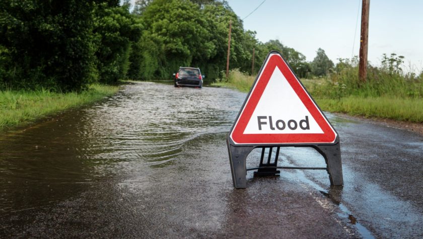 A sign for flood on a flooded road