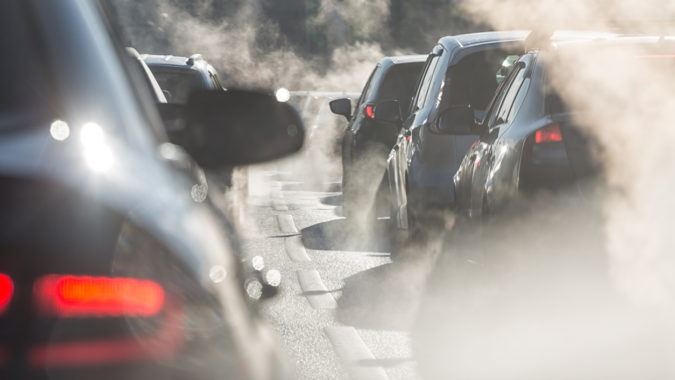 Blurred silhouettes of cars surrounded by steam from the exhaust pipes