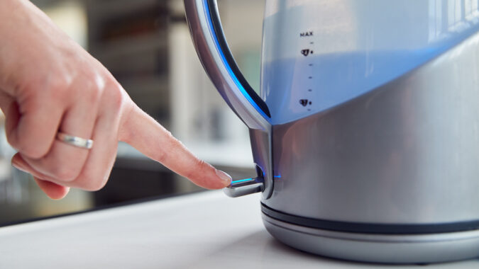 Woman turning on an electric kettle