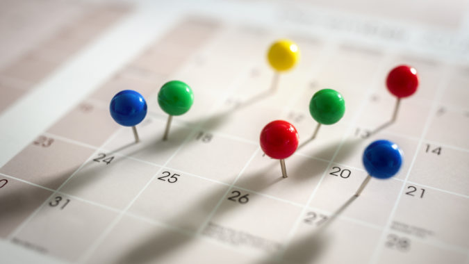 Thumbtack pins in calendar concept for busy, appointment and meeting reminder
