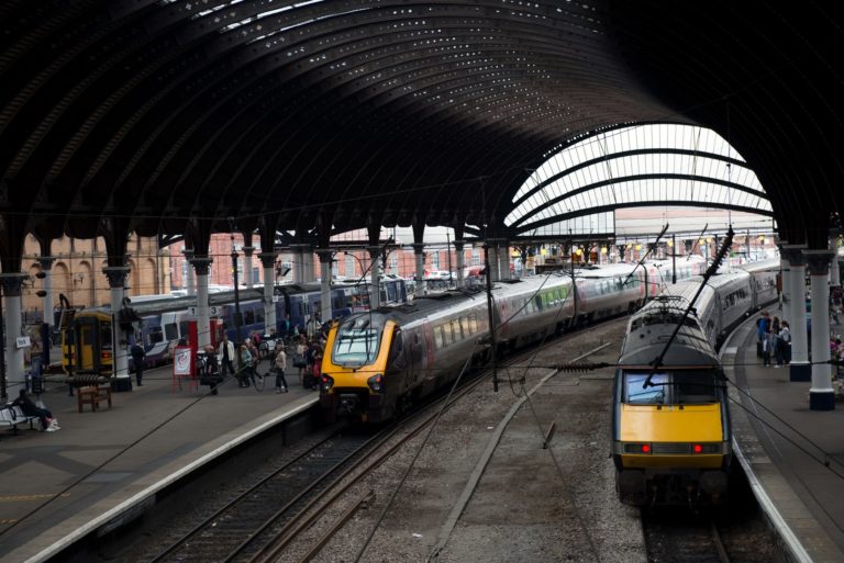 York, UK - August 05, 2013: York railway station where the platforms curve under the famous glass and iron curved arched roof. Train awaits departure to London. Some passengers are waiting train for departure.