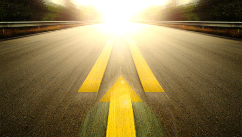 A blurred road moving towards the sun