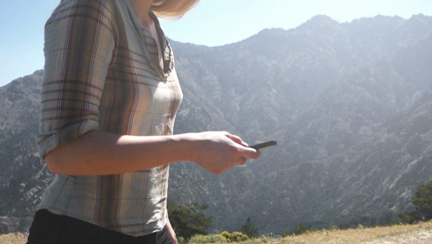 Woman using smartphone in mountain range