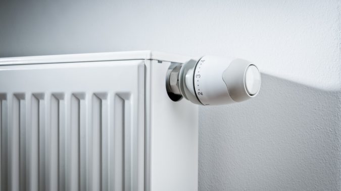 Modern white radiator with thermostat reduced to economy mode