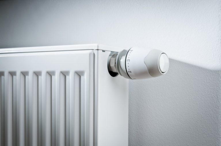Modern white radiator with thermostat reduced to economy mode
